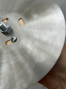 This effect was created by making a fixture to spin the plate in a drill press and then applying sandpaper.